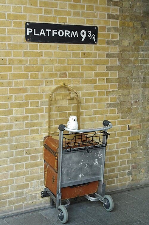 Platform 9¾ sign above a luggage trolley and snowy owl at King’s Cross station